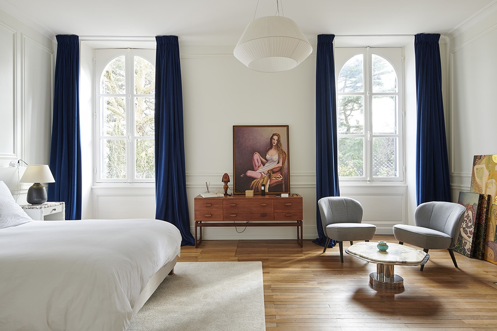 Chambre à coucher lumineuse. Fenêtre cintrées blanche, moulures sur les murs.