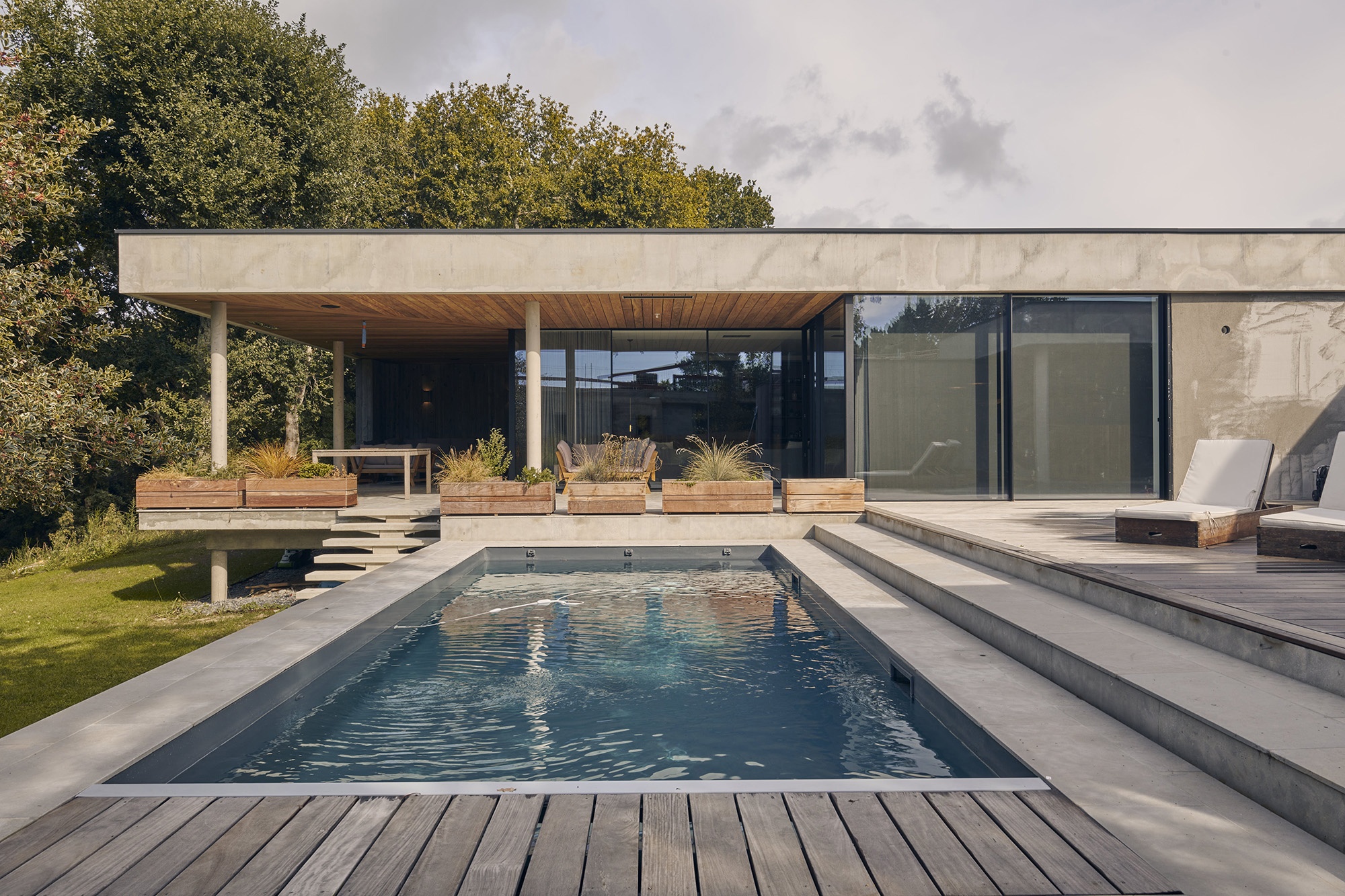 Maison d'architecte moderne en béton. Piscine et terrasse en premier plan.