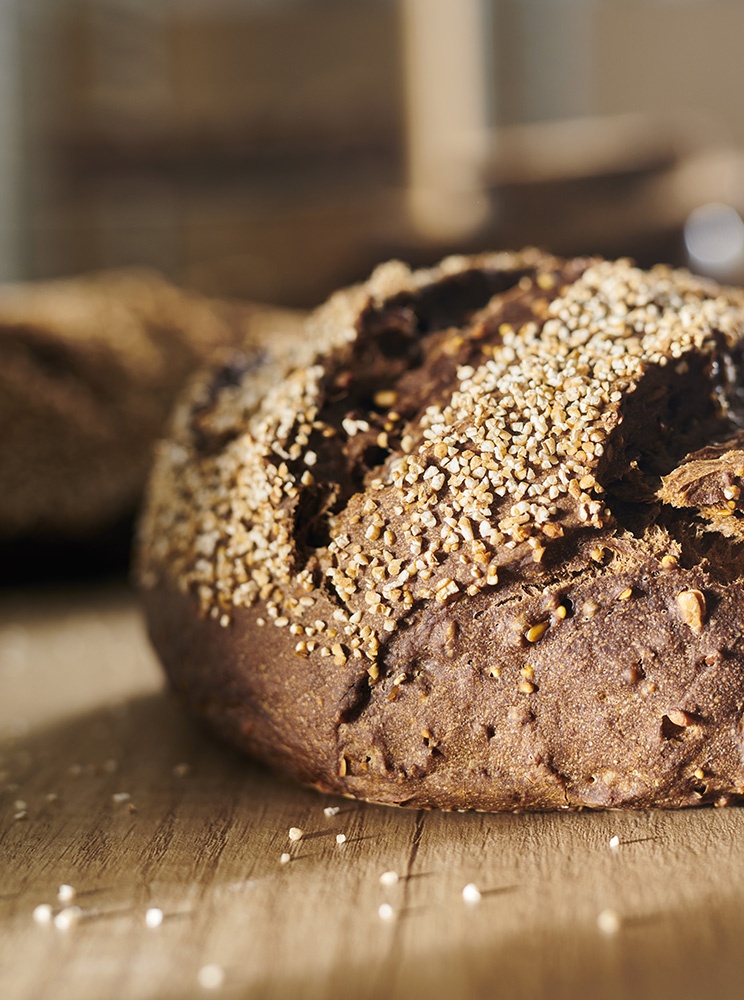 Close-up avec un éclairage travaillé sur une miche de pain aux céréales : c'est le pain nordique de LA MIE CALINE