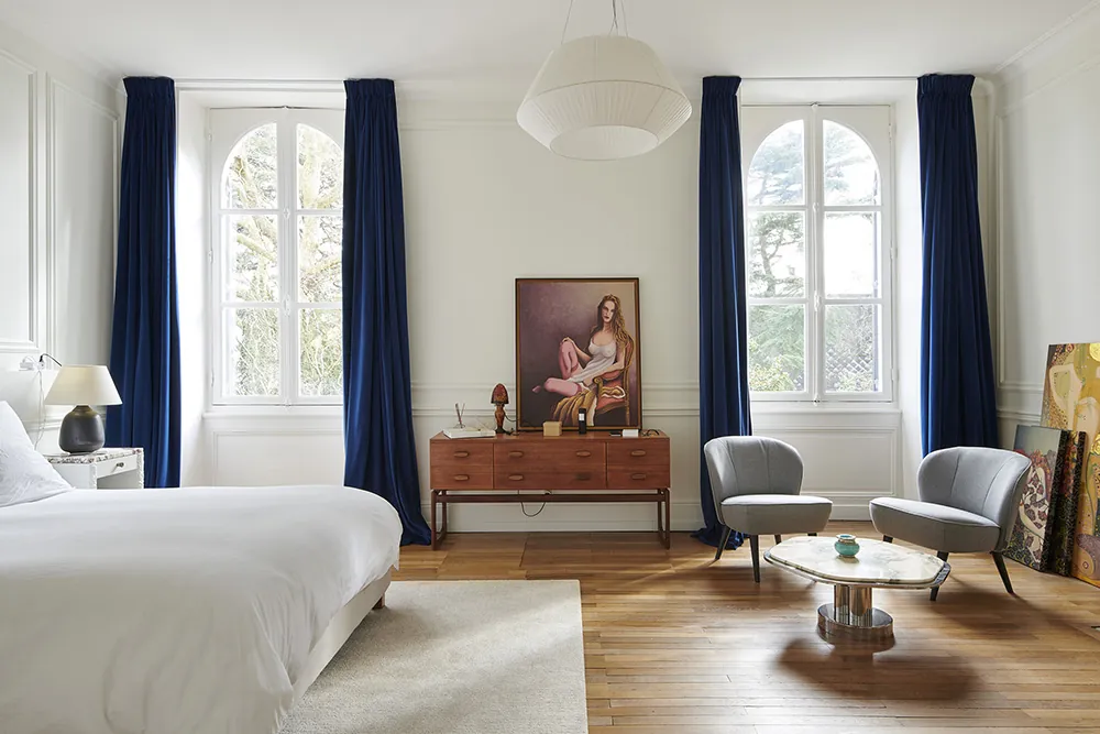 Chambre à coucher lumineuse. Fenêtre cintrées blanche, moulures sur les murs.
