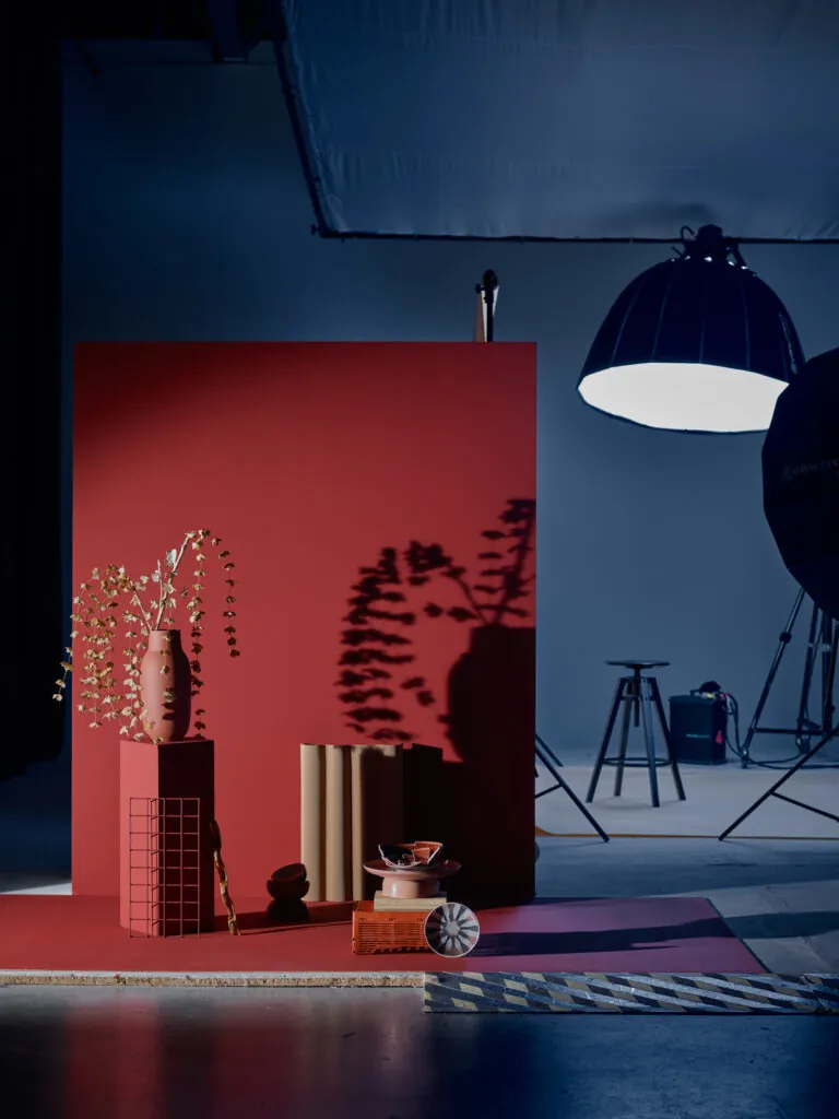 Décors dans un espace cyclo d'un studio de photographie. Du matériel photo un set design composé d'un fond principal rouge et d'accessoires de décoration.